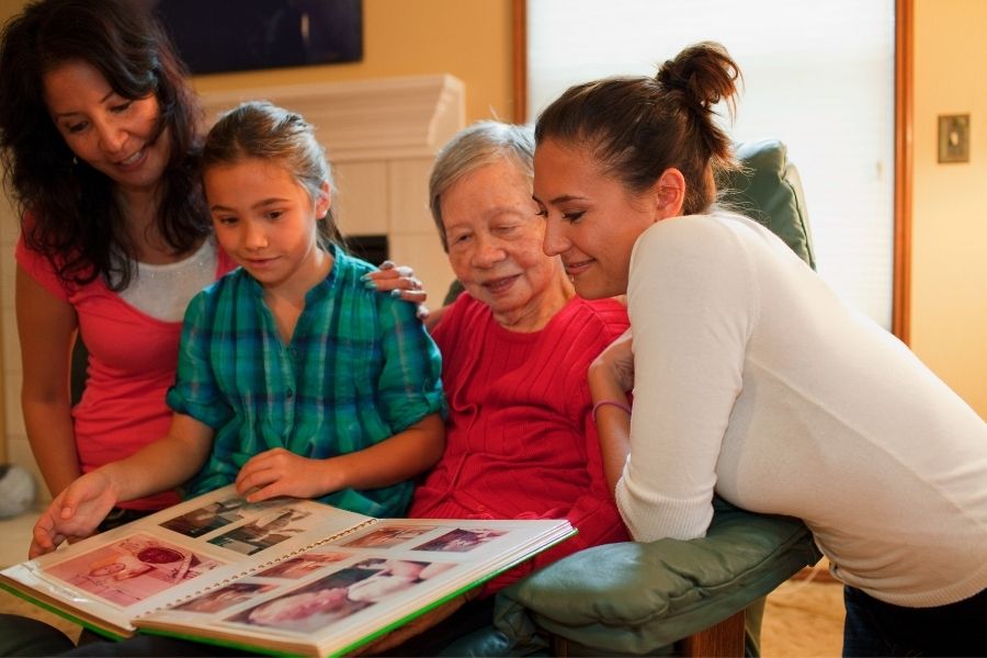 Mom with daughter and grandmother looking at family photos having Screen Free family time